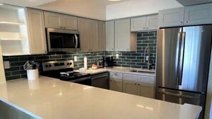 A modern kitchen with a large island, stainless steel appliances, and light-colored cabinetry.