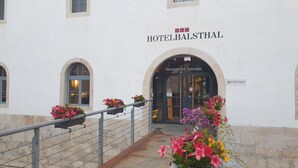 Entrada de un hotel con un letrero que dice "HOTELBALTHAL" y un arco que indica "Restaurante Lounge".