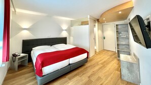 Una habitación de hotel moderna con una cama, una mesita de noche y un televisor montado en la pared.