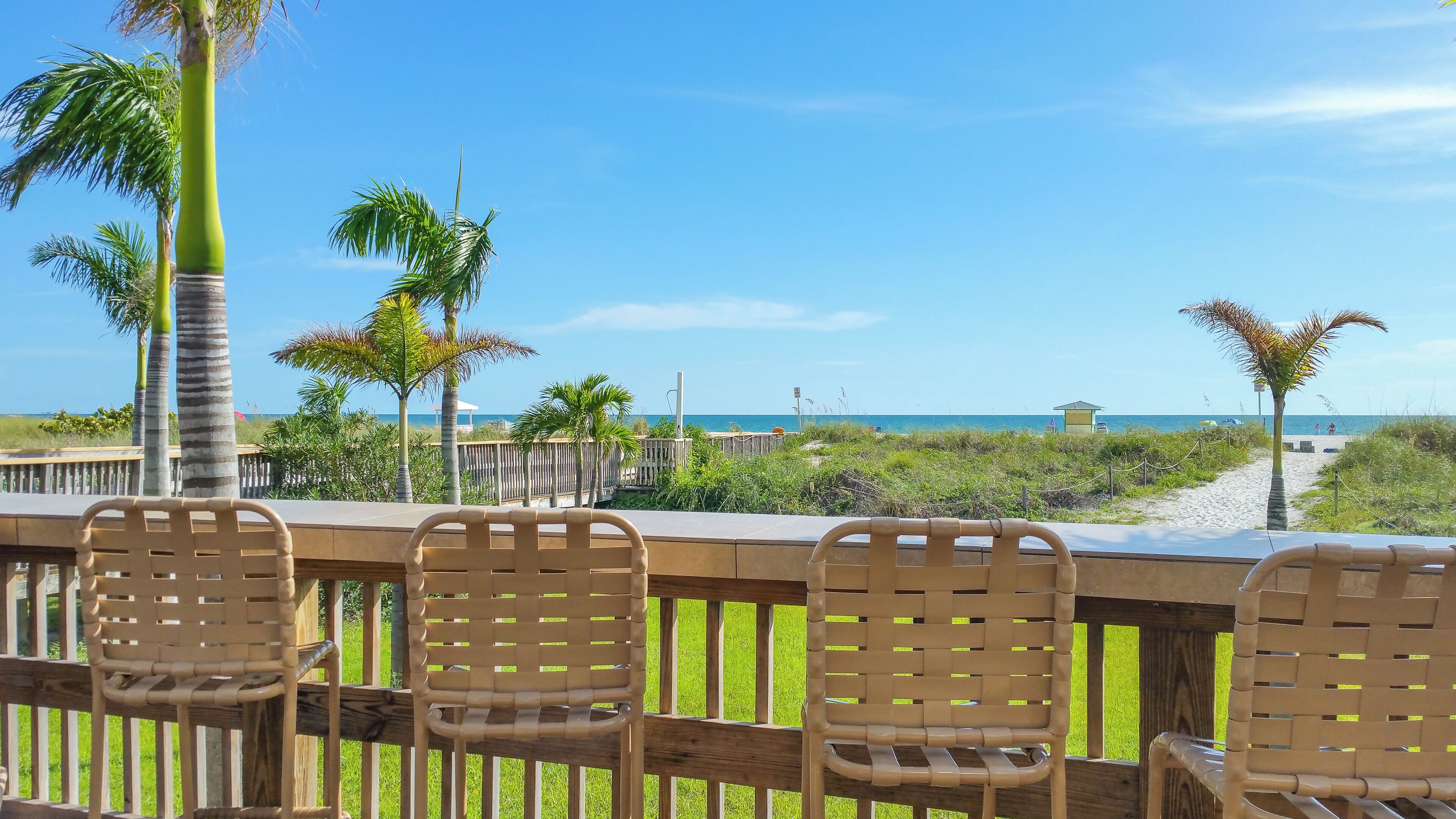 Une terrasse en bois avec des chaises donnant sur une plage.