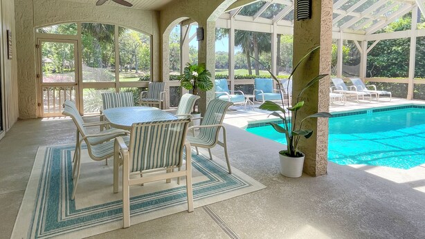 Eine überdachte Terrasse mit Pool, Sitzgelegenheiten und Deckenventilatoren.