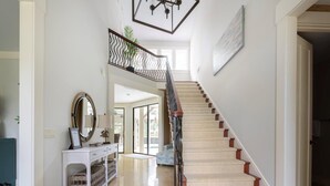 Eine Treppe mit hölzernem Geländer und beigefarbenen Teppichstufen, die zu einer zweiten Etage führt.