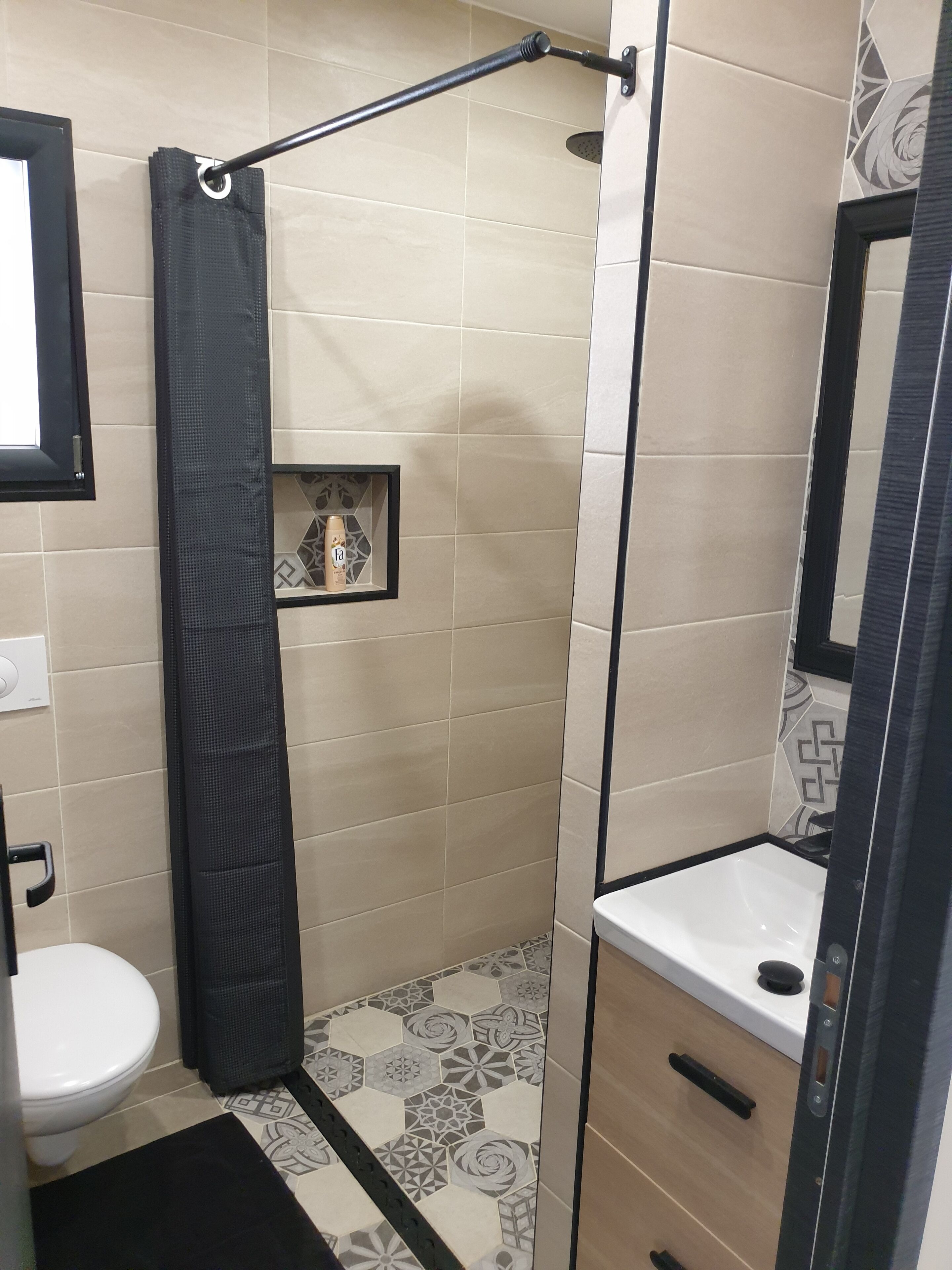 Een badkamer met douche, toilet en wastafel.