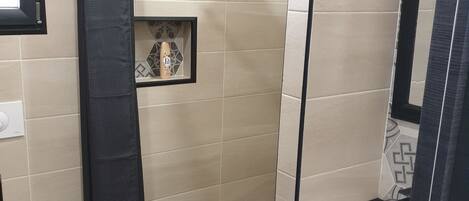 Een badkamer met douche, toilet en wastafel.