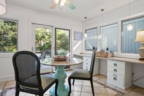 A kitchen with a round table, two chairs, a window with a view of trees, and a ceiling fan. - 19 Gunnery Lane at The Sea Pines Resort (Hilton Head Island)