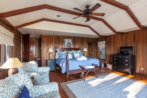 A bedroom with a large bed, wooden walls, a ceiling fan, and a television. - 41 South Beach Lagoon at The Sea Pines Resort (Hilton Head Island)
