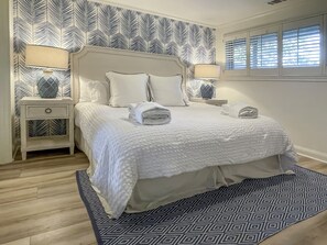 A neatly made bed with a white duvet and pillows, a bedside table with a lamp, and a patterned rug. - 80 Fairway Lane at The Sea Pines Resort (Hilton Head Island)