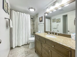A bathroom with a shower, toilet, vanity with a sink, and a large mirror. - 482 Plantation Club at The Sea Pines Resort (Hilton Head Island)
