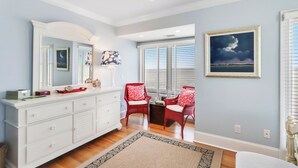 A bedroom with a white dresser, two red chairs, a large mirror, and a framed picture on the wall. - 720 Schooner Court at The Sea Pines Resort (Hilton Head Island)