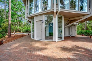A modern house with a glass extension, surrounded by a brick pathway and lush greenery. - 2075 Deer Island at Sea Pines Resort (Hilton Head Island)