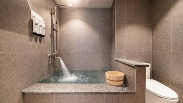A modern bathroom with a shower, a toilet, and a wooden bucket.