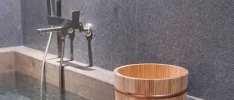 A wooden bowl with a copper band on a stone ledge by a pool.