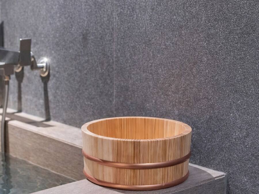 A wooden bowl with a copper band on a stone ledge by a pool.