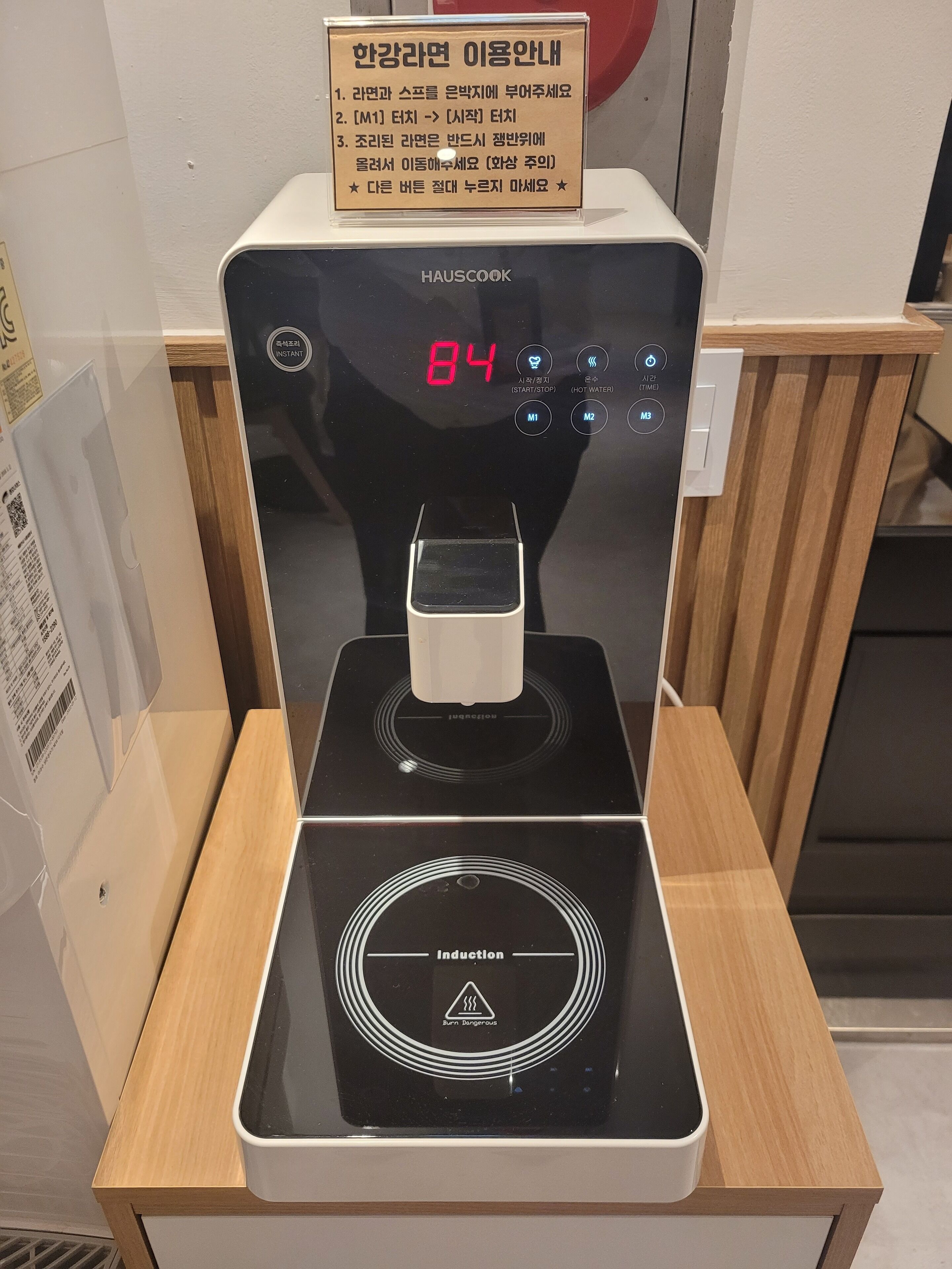 A modern induction cooktop with a digital display, a control panel, and a wooden table.