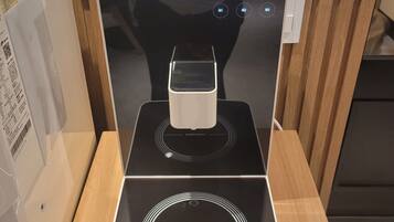 A modern induction cooktop with a digital display, a control panel, and a wooden table.