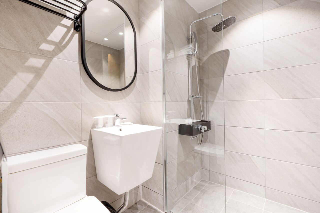 A modern bathroom with a glass shower enclosure, a white sink, and a mirror.