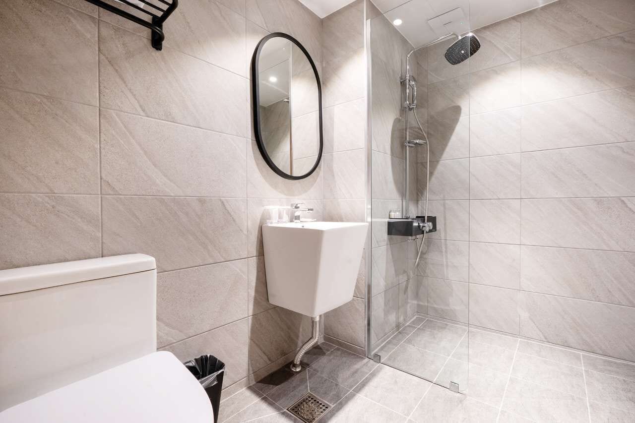 A modern bathroom with a toilet, sink, and glass-enclosed shower.