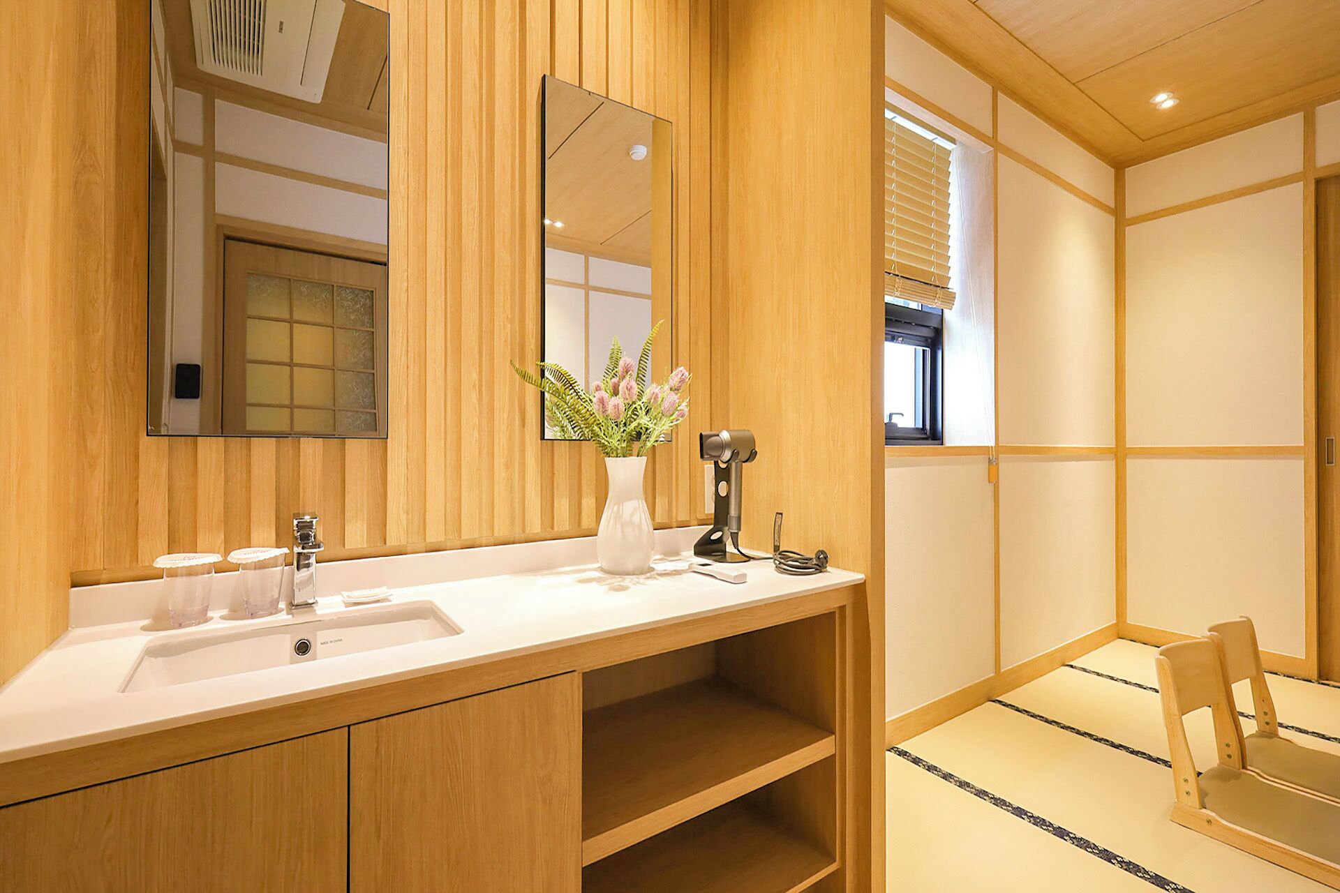 Un baño de madera con un espejo grande, un lavabo, un tocador y una silla.
