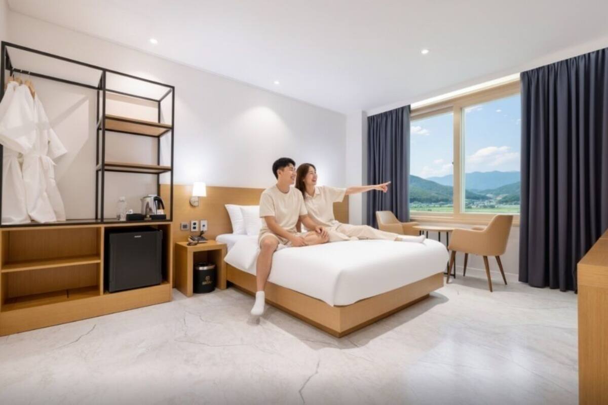 Una habitació d'hotel moderna amb un llit gran, un escriptori i vistes a l'exterior.