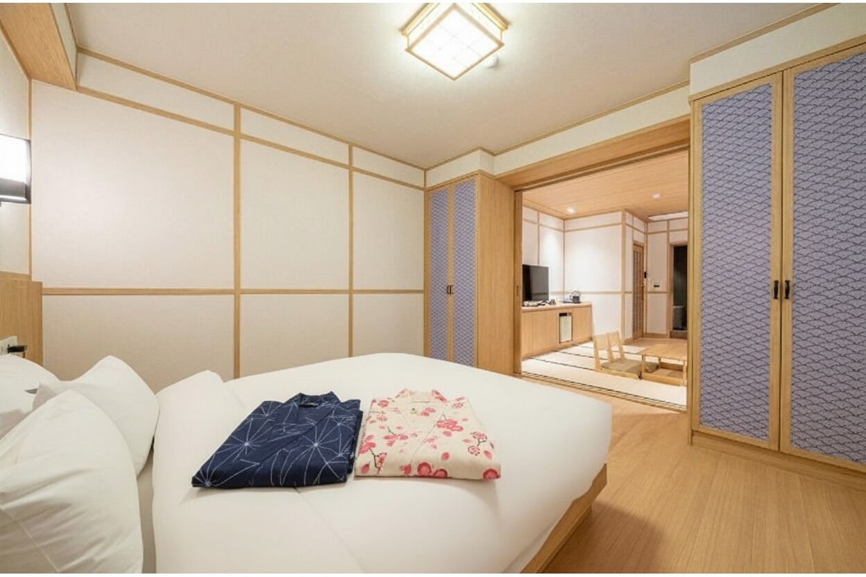 Quarto de hotel com uma cama, uma escrivaninha e um guarda-roupa.