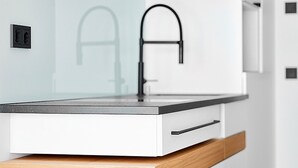 A modern kitchen with a white countertop, a black faucet, and a wooden drawer unit. - Livisit bergapartment 35 - double room 27 sqm - with south-facing balcony (Stuttgart)