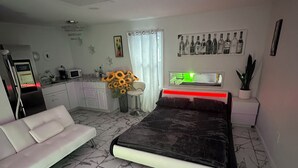 Ein modernes Schlafzimmer mit einem großen Bett, einer Couch, einer Küchenzeile und einem Esstisch.