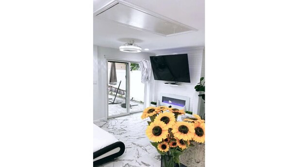 Ein modernes Hotelzimmer mit Bett, Flachbildfernseher an der Wand, Kamin und großem Fenster.
