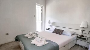 A minimalist bedroom with a bed, bedside tables, and a window. - Central Apartment Bol (Bol)