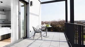 Een modern balkon met een eethoek, inclusief een tafel en stoelen, en een uitzicht op de stad.