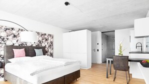 Een moderne slaapkamer met een groot bed, een bureau en een kitchenette.