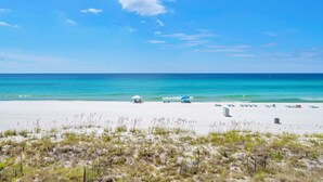 Une plage de sable blanc, avec une eau turquoise et limpide, et quelques parasols.
