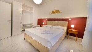 Una habitación de hotel con una cama grande, un armario, una mesita de noche con una lámpara y un adorno en la pared.