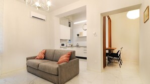 Una sala de estar moderna con un sofá, un comedor con mesa y sillas, y una cocina al fondo.