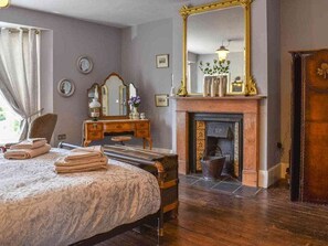 A traditional bedroom with a bed, a dresser, a mirror, and a fireplace.