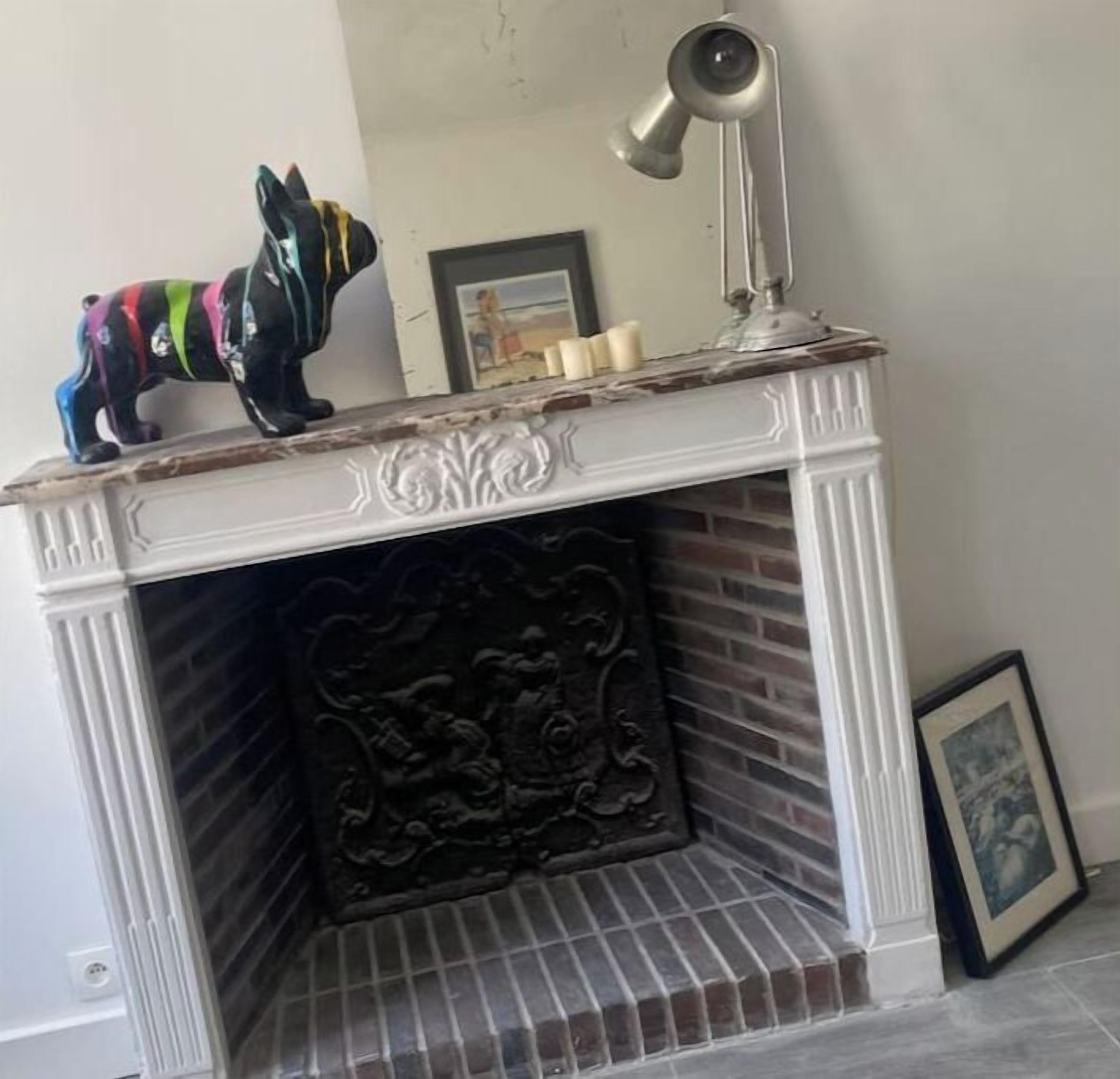 A fireplace with a decorative mantel, a framed picture, and a small figurine.