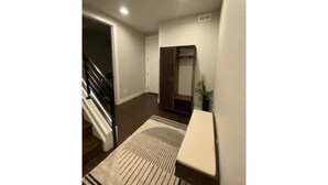 Un couloir avec un escalier, une porte et une petite table.