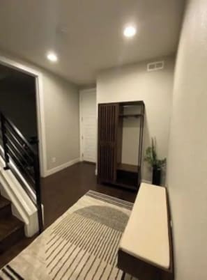 Un pasillo con una escalera, una puerta y una pequeña mesa.