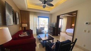 Een hotelkamer met een rode bank, een zwarte fauteuil, een salontafel, een televisie en een bed.