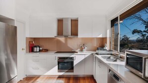 A modern kitchen with white cabinets, a built-in oven, and a window providing a view of the outdoors.