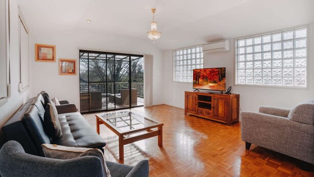 A spacious living room with a large TV, comfortable seating, and large windows.