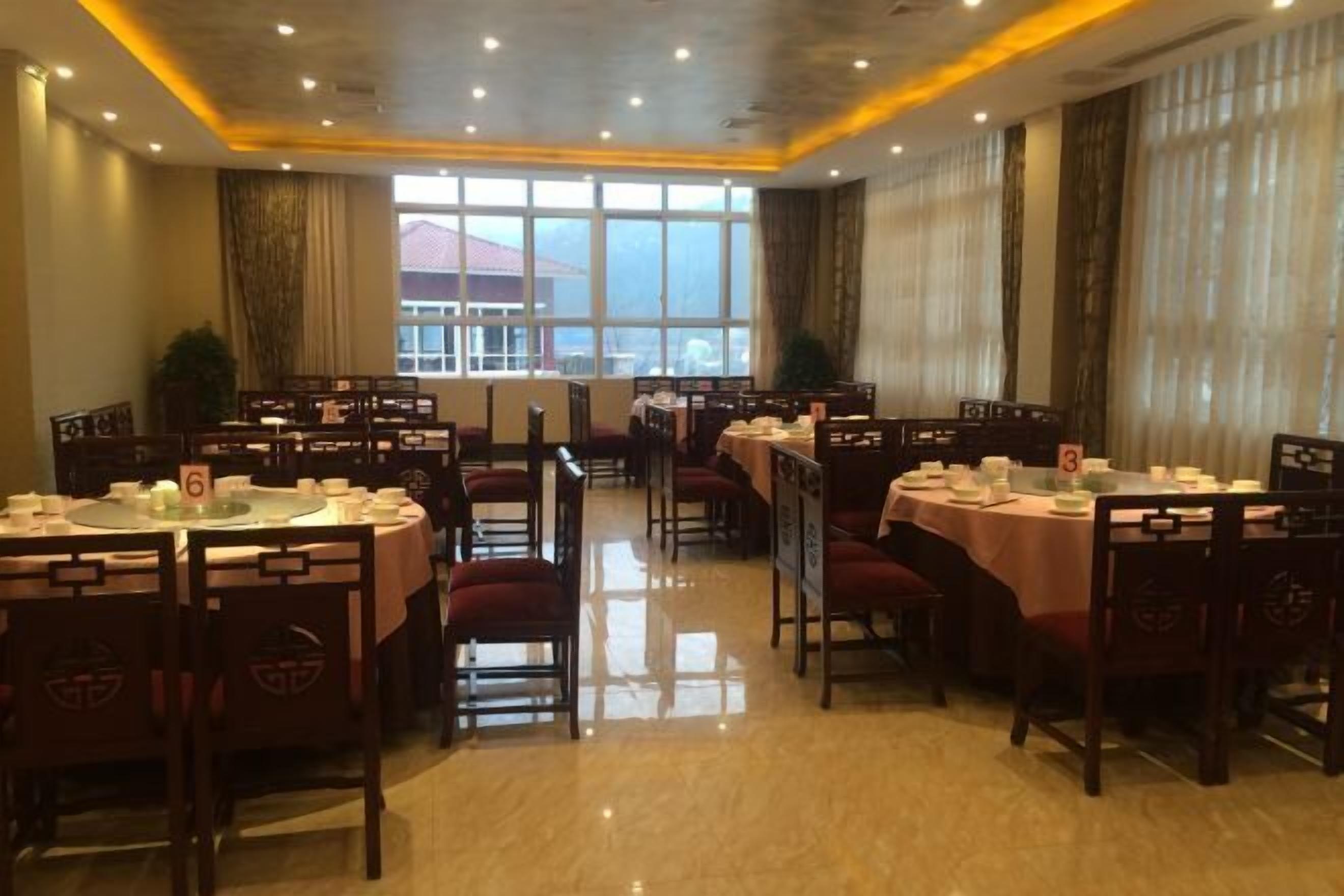 A restaurant with round tables, chairs, and a large window offering a view.
