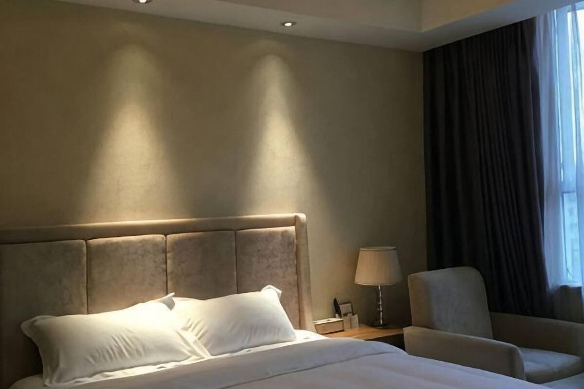 A hotel room with a large bed, a nightstand, a chair, and a window with curtains.