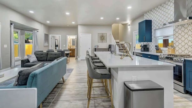 A modern kitchen with a central island, a dining area with a sofa and chairs, and a living room with a sofa and a coffee table.