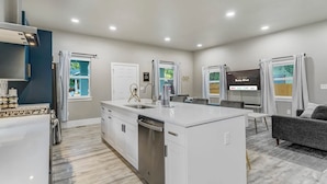 A modern kitchen with a central island, built-in appliances, and a dining area with a flat-screen TV.