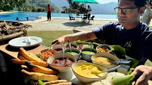 Una mesa de comedor con varios platos, una piscina y montañas al fondo.