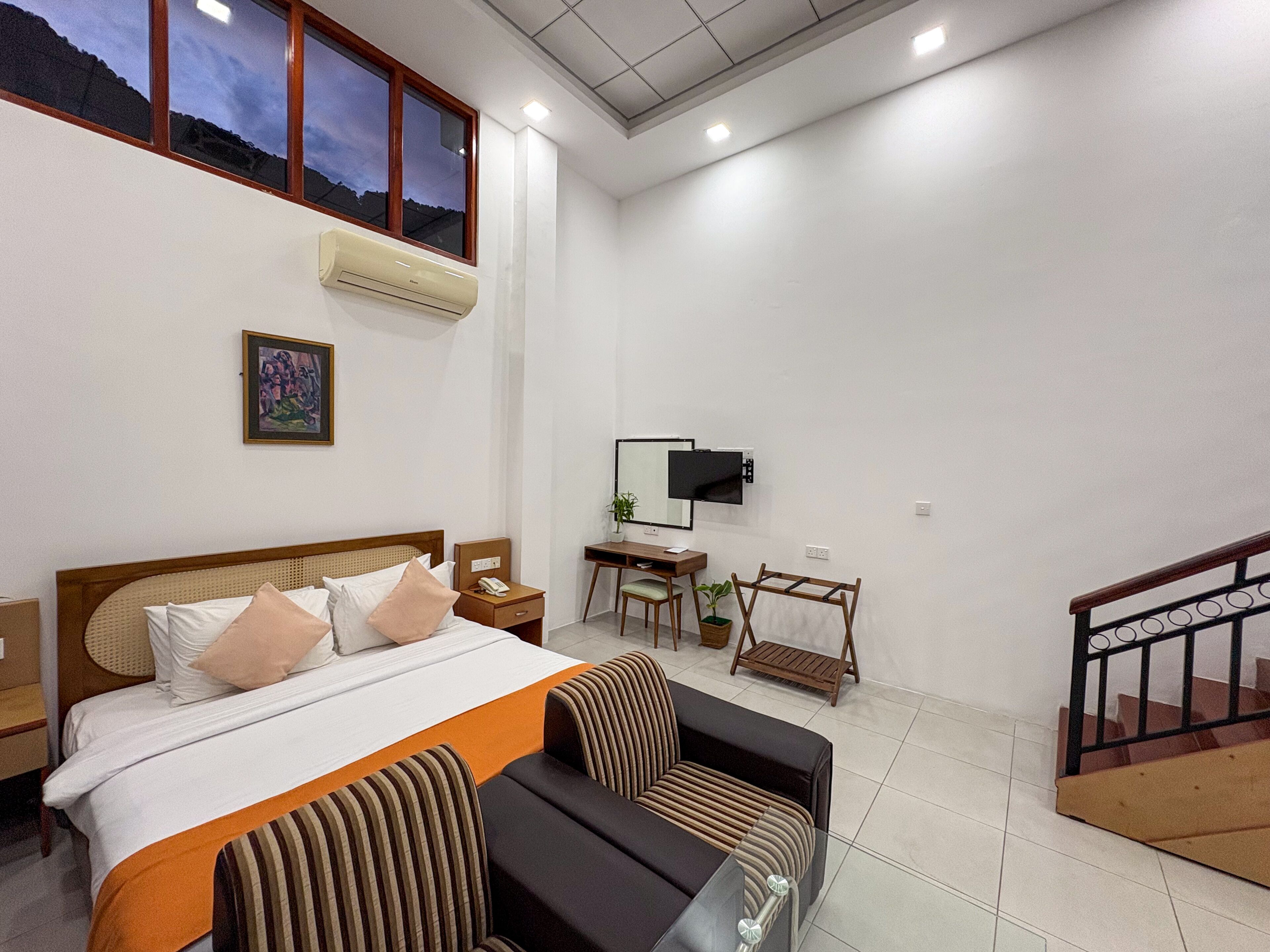 A hotel room with a bed, a desk, a TV, and a staircase.