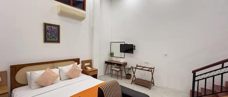 A hotel room with a bed, a desk, a TV, and a staircase.