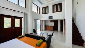 Amplia habitación de hotel con una cama grande, un sofá, un área de comedor y una escalera.