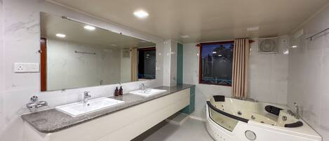 A modern bathroom with two sinks, a large mirror, a bathtub, and a window with curtains.