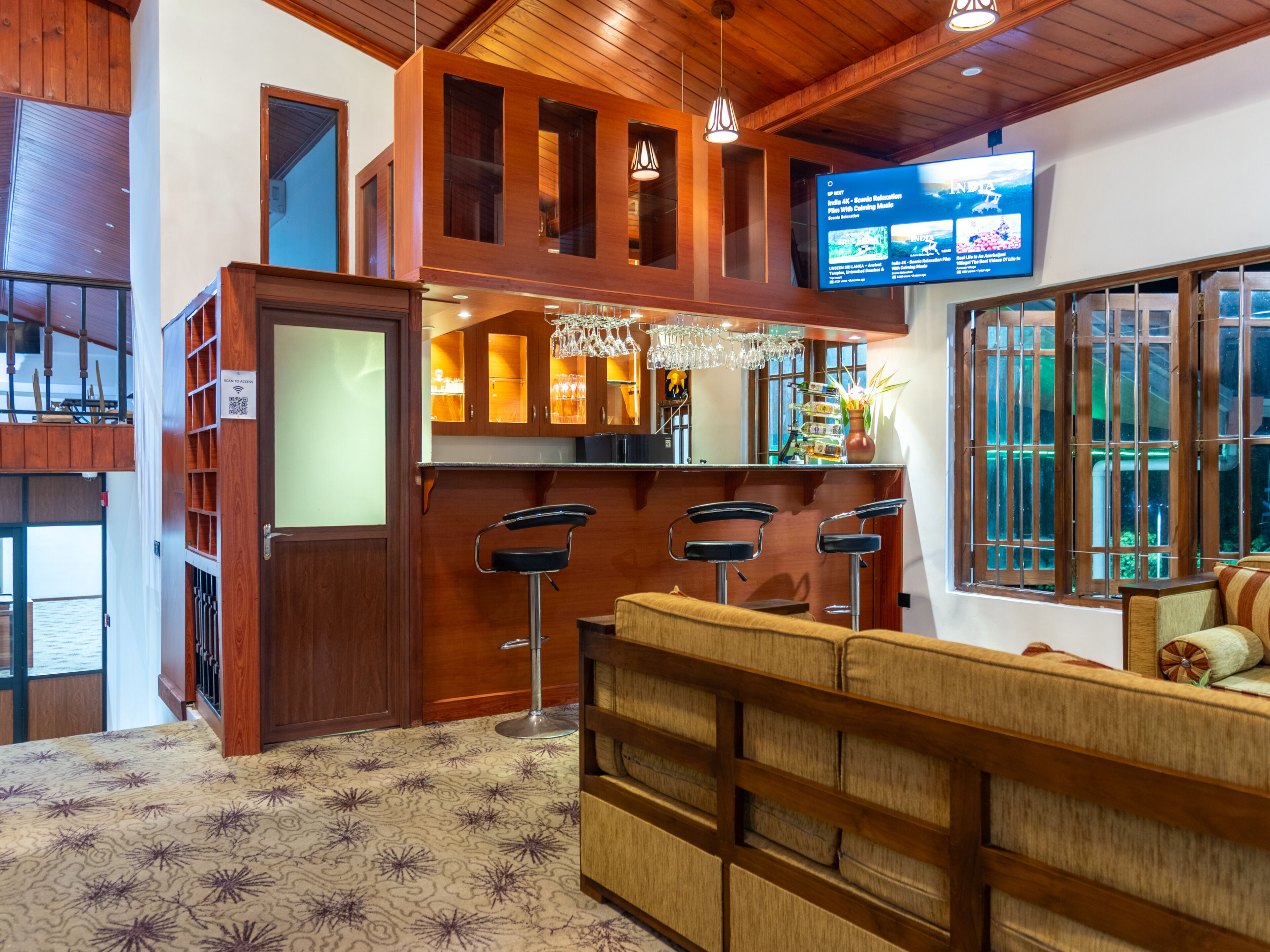 A bar area with wooden furnishings, a television screen, and a patterned carpet.